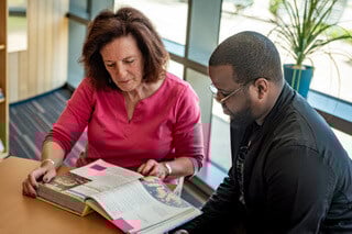 A man and woman reading a textbook together